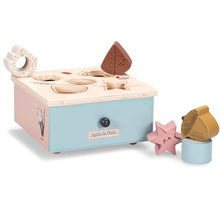 A wooden shape sorter box with various wooden sorting pieces displayed in front, including a kaleidoscope piece, presented in pastel colors.
