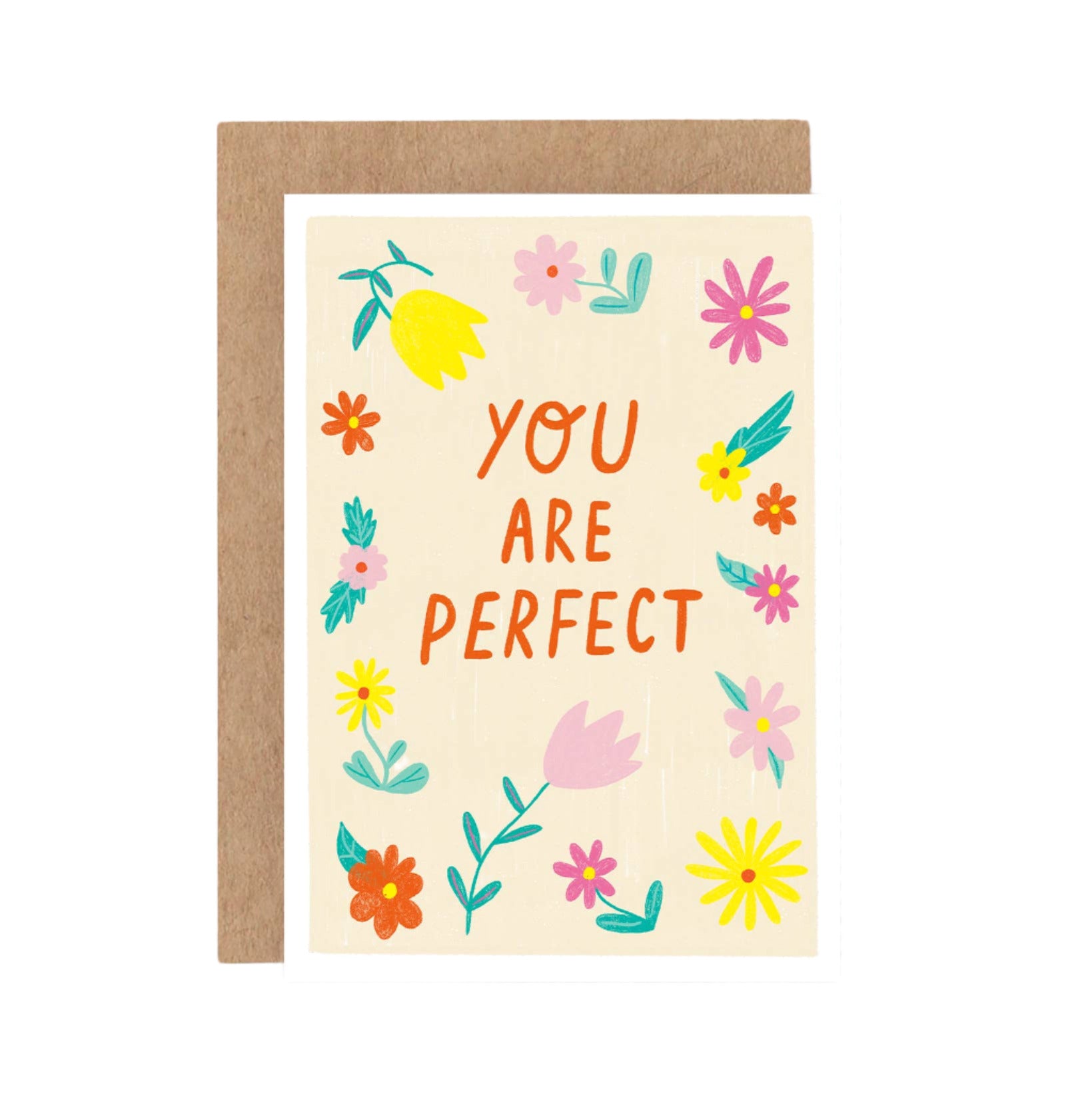 A greeting card with the text 'YOU ARE PERFECT' surrounded by colorful floral illustrations, set upon a beige background. A brown envelope is included.