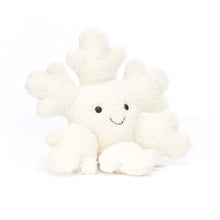 A plush toy resembling a snowflake with a smiling face and fluffy cream-colored branches.