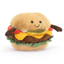 A plush toy resembling a burger with a smiling face, dressed in a two-tone golden bun, cordy arms, a fluffy green gherkin, yellow cheese, and foldy lettuce.