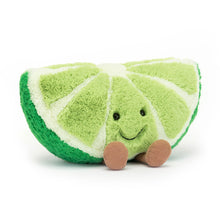 A plush toy in the shape of a slice of lime with a smiling face, fine-cord legs, and a green textured body.