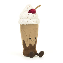 A plush toy designed to look like a chocolate milkshake with a cherry on top and cocoa cordy legs.