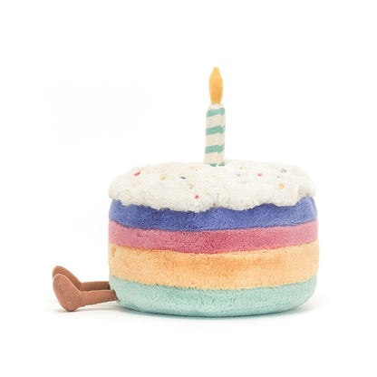 Stuffed toy resembling a birthday cake with a candle on a white background