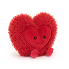 A bright red plush toy in the shape of a heart with a smiling face and a fluffy mane.