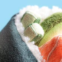 Close-up of a textured fabric resembling the interior of a sushi roll with green, orange, and white patterns against a blue background
