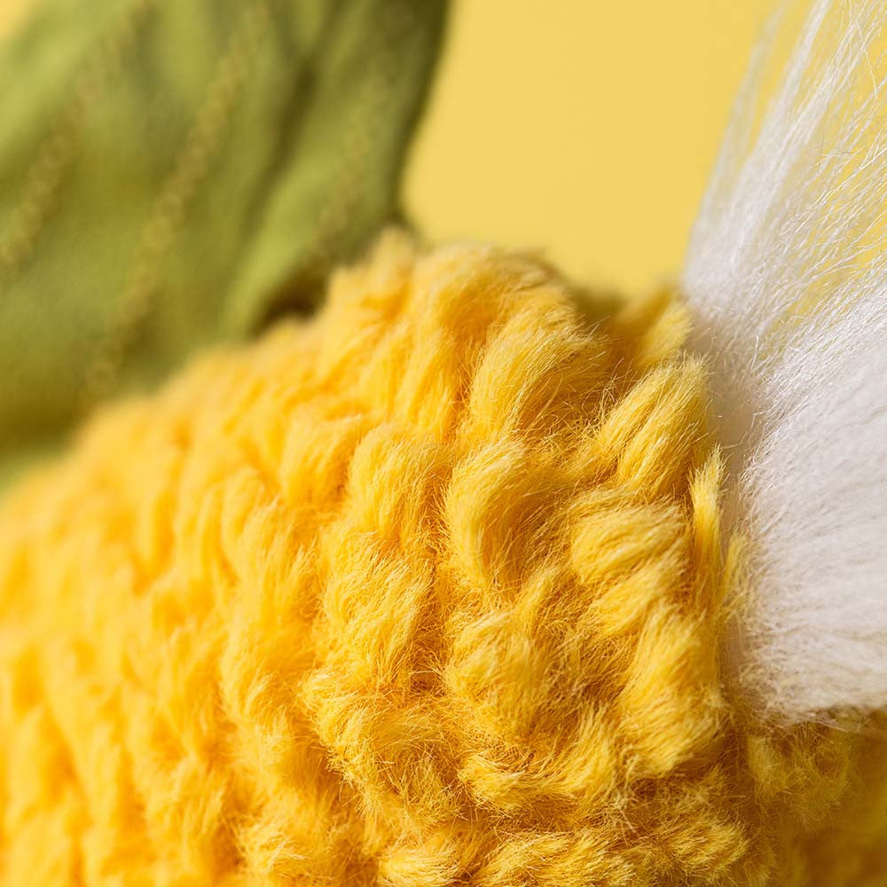 Close-up of yellow yarn with a blurred green leaf in the background