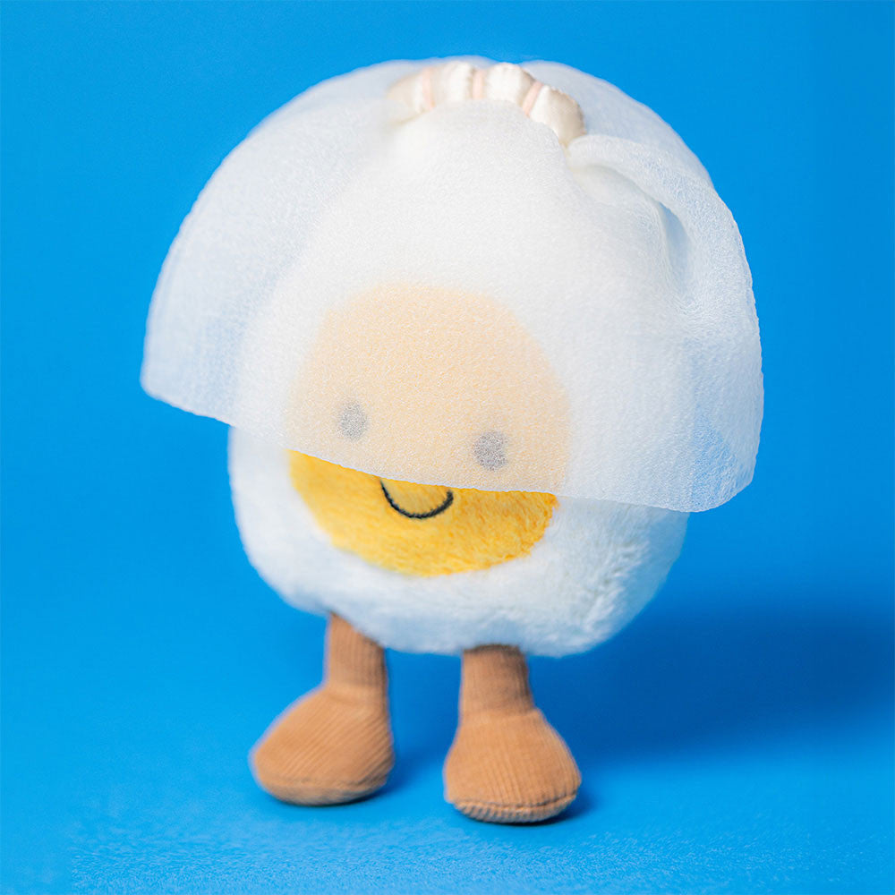 Jellycat egg soft toy with brown legs, wearing a bridal veil, against a blue background.