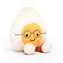 A plush toy resembling a boiled egg with a face, wearing glasses and red shoes, made by Jellycat.