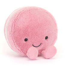 Pink plush macaroon toy with a smiling face on a white background