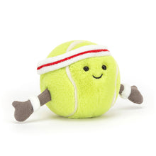 A soft plush toy resembling a tennis ball with a happy facial expression, wearing a headband and wristbands. The toy is primarily yellow with a green texture and red and white accents.