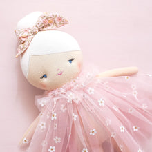 Stuffed doll in a pink tutu with floral headband on a light pink background