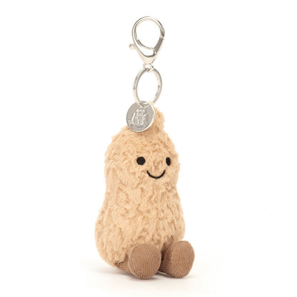 Jellycat Plush keychain shaped like a peanut with a smiling face on a white background