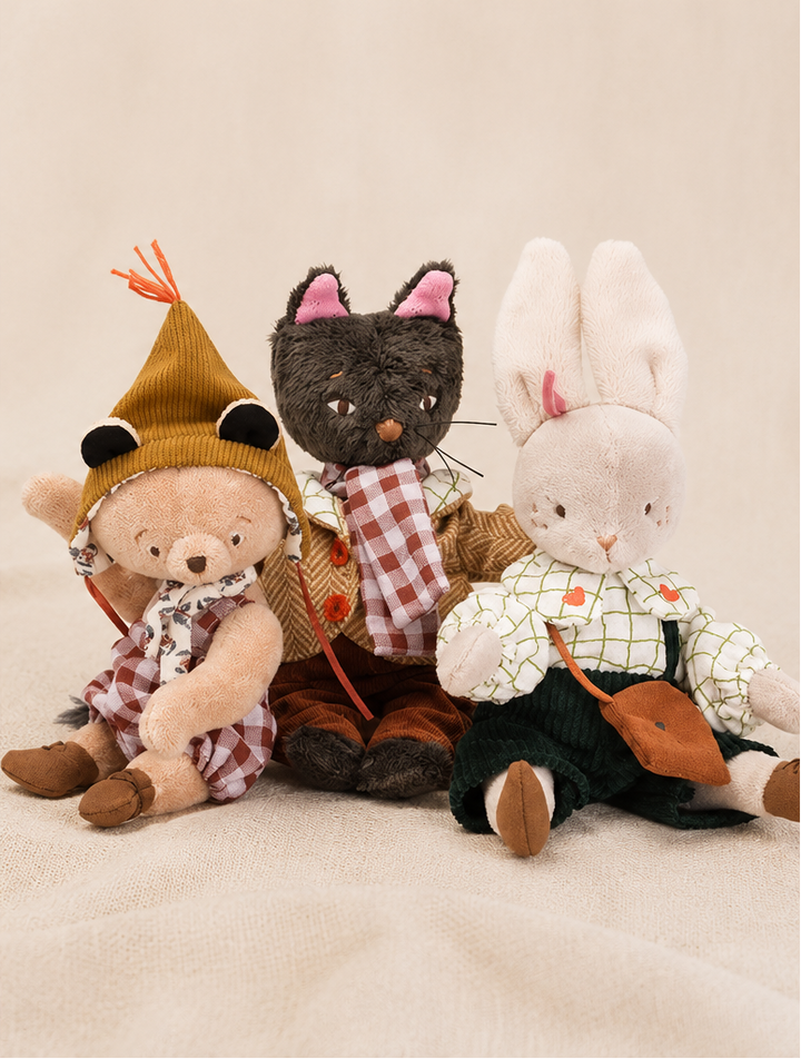 Three plush toys, including a bear, cat, and rabbit, dressed in checkered outfits on a beige background.