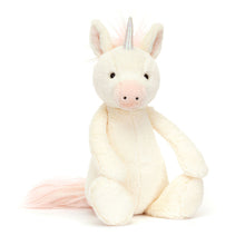 A plush toy resembling a unicorn with soft vanilla fur, pink inner ears, a squashy holographic horn, and a pink tail.
