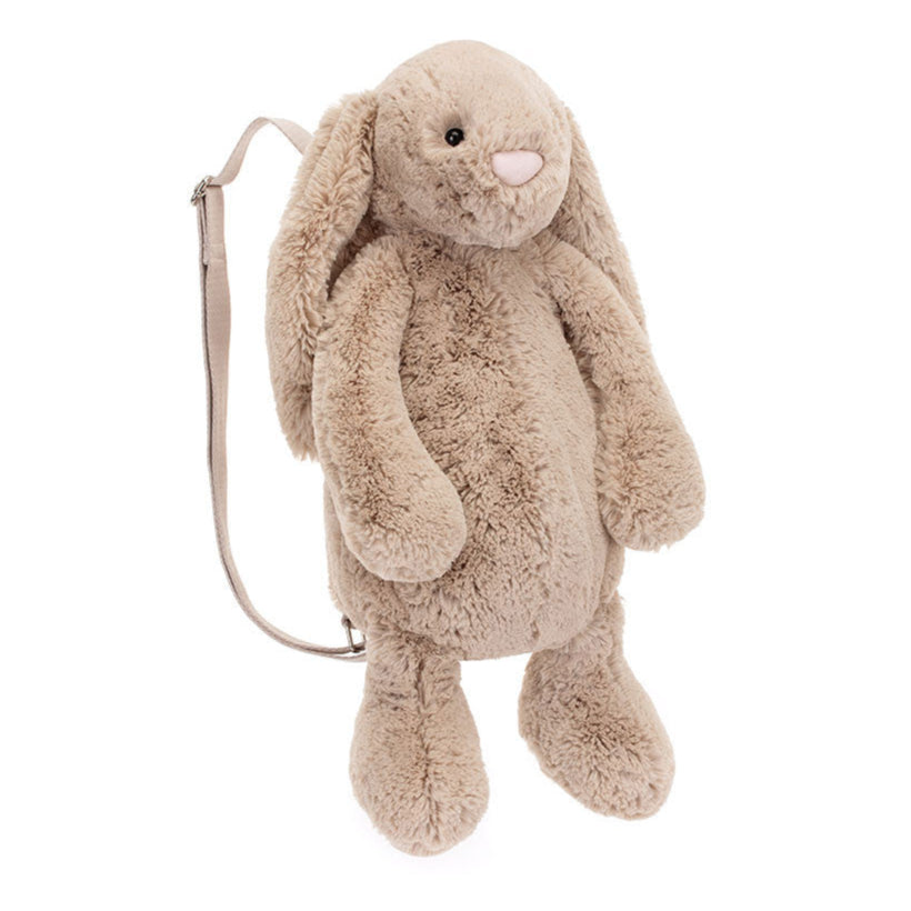 A beige plush backpack designed to look like a bunny with wide adjustable straps and a zip closure. Backpack is Jellycat brand.