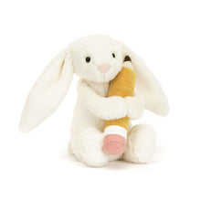 A plush toy depicting a cream-colored bunny holding a pencil with a grey tip and a pink eraser.