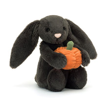 A plush toy depicting a brown bunny holding an orange pumpkin with a green stem.