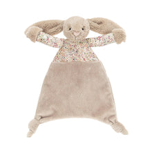 A beige plush toy in the shape of a bunny with a flower-print top and a silky tum.