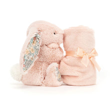 A blush pink Jellycat soother with a plush bunny attached to a floral-patterned blanket, wrapped with a pink ribbon.