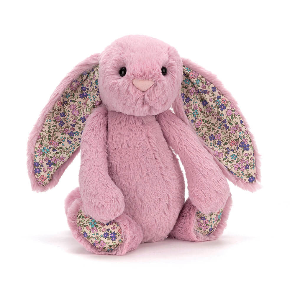 A small pink stuffed bunny with floral fabric details on its ears and feet.