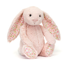 A small plush toy resembling a bunny with blush-pink fur, floral ears, and feet, set against a plain background.