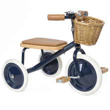 A navy blue and black tricycle with a brown seat and wicker basket, designed for young children.
