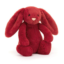 A plush toy representing a sitting red bunny with long ears, a pink nose, and a fluffy tail.