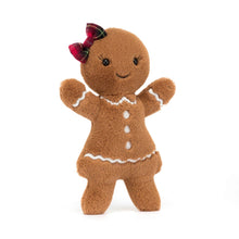 A large plush toy resembling a gingerbread man with a stitched icing dress, embroidered lashes, a tartan hair bow, and biscuit arms.