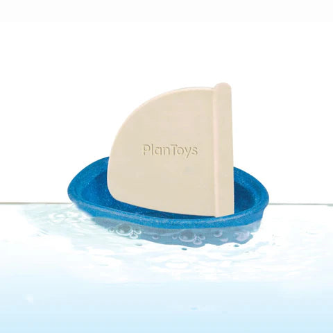 A small blue wooden sailing boat with white rubber mast. The mast is printed with the word PlanToy.
