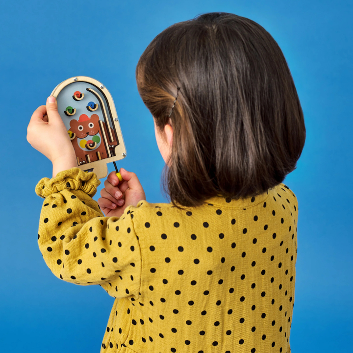 Child holding a wooden toy with a blue background