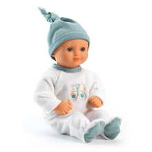 A soft body doll named Neige Pomea, dressed in white pajamas and a blue hat, with a neutral-scented vinyl head, arms, and legs.