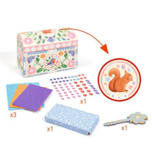 Children's craft kit with decorative box, paper, stickers, and a key-shaped object on a white background.