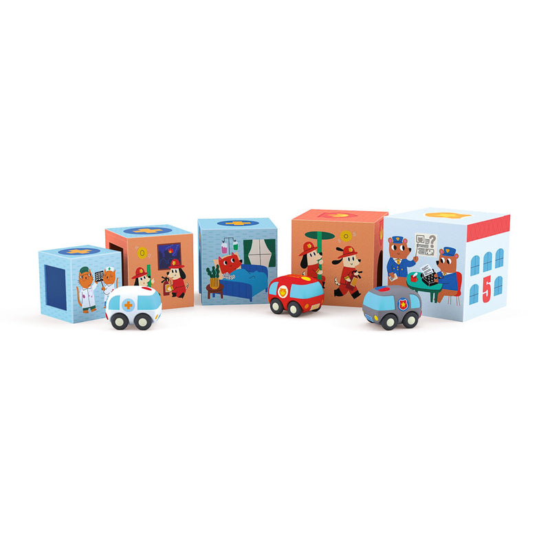 Illustrated card blocks with buildings like a fire station and a hospital, along with three soft-plastic vehicles including an ambulance, a fire engine, and a police car.