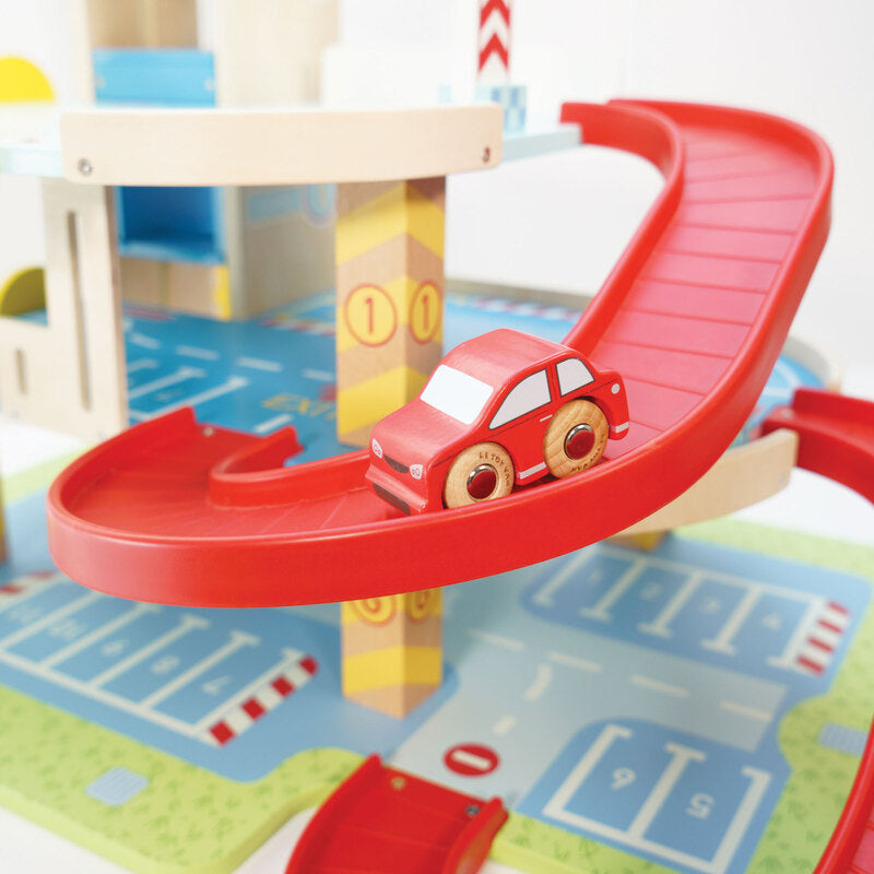 Toy car on a red track with a wooden tower and colorful mat in the background
