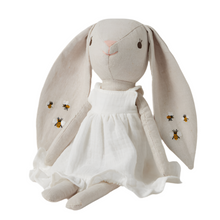 Stuffed toy in the shape of a bunny with a white floral dress and embroidered details, including bees on the skirt.