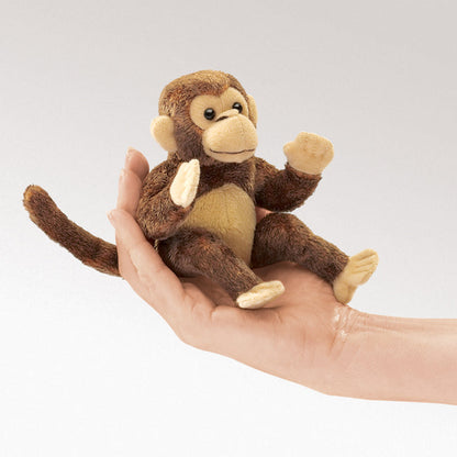Small plush monkey toy held in a hand against a light gray background