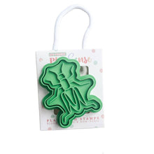 A green playdough stamp in the shape of a grasshopper, packaged with a white hanging card.