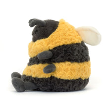 A plush toy resembling a bumblebee with thick yellow and black striped fur, charcoal legs, and soft cream wings.