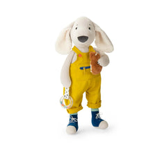 Dog soft toy with floppy cream ears, blue sneakers and yellow overalls, holding a ring rattle and small hamster plush