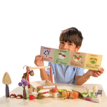 Child holding educational cards with a wooden play set on a white background