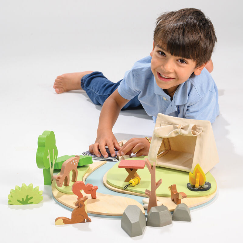 Child playing with a wooden playset on a white surface