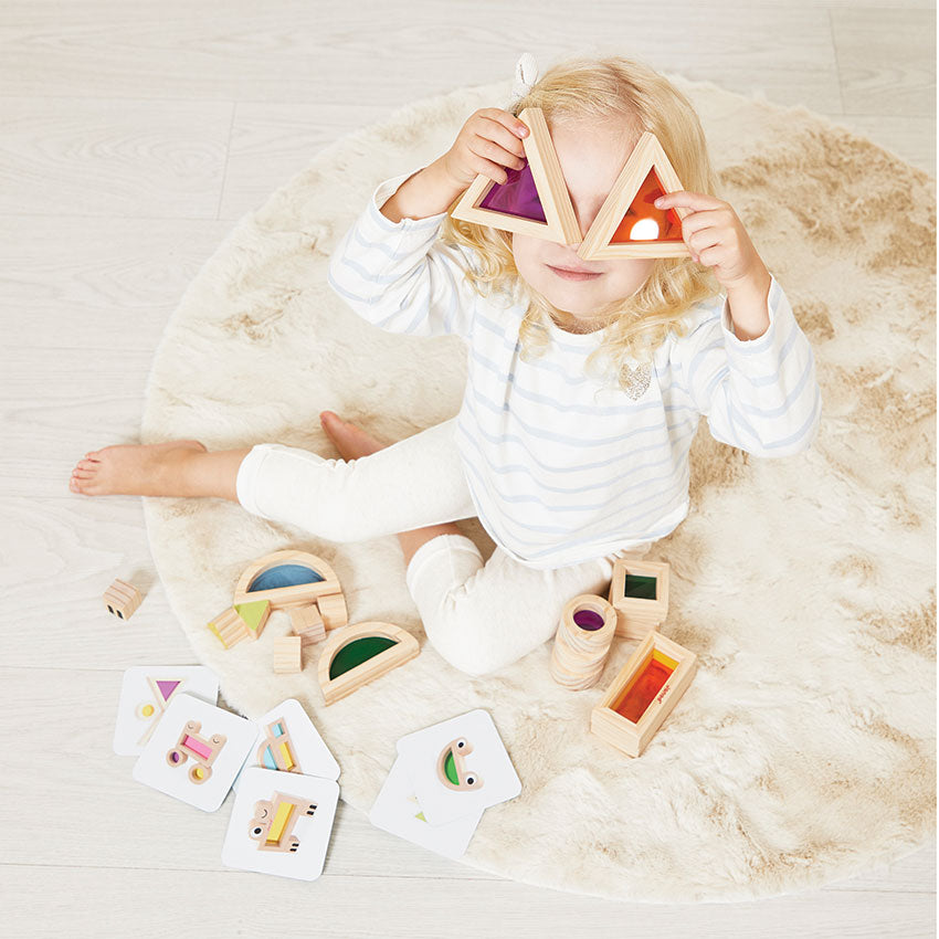 Child playing with wooden shape sorting toys on a soft surface