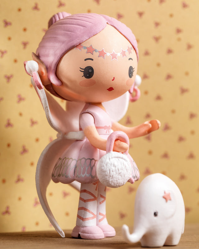 Toy figure of a girl with pink hair and a small white elephant on a patterned background