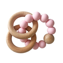 Teething ring with pink beads and wooden rings on a white background