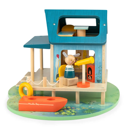 Wooden toy house with a boat and rabbit figure on a white background