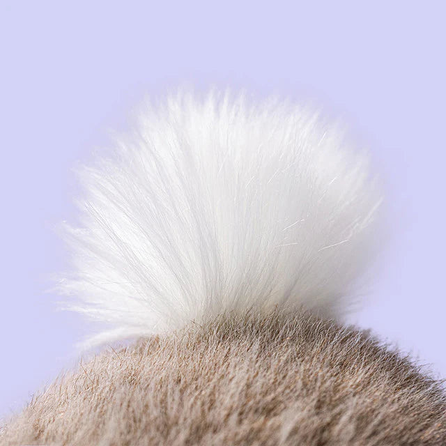 Close-up of a fluffy white bunnytail against a light purple background
