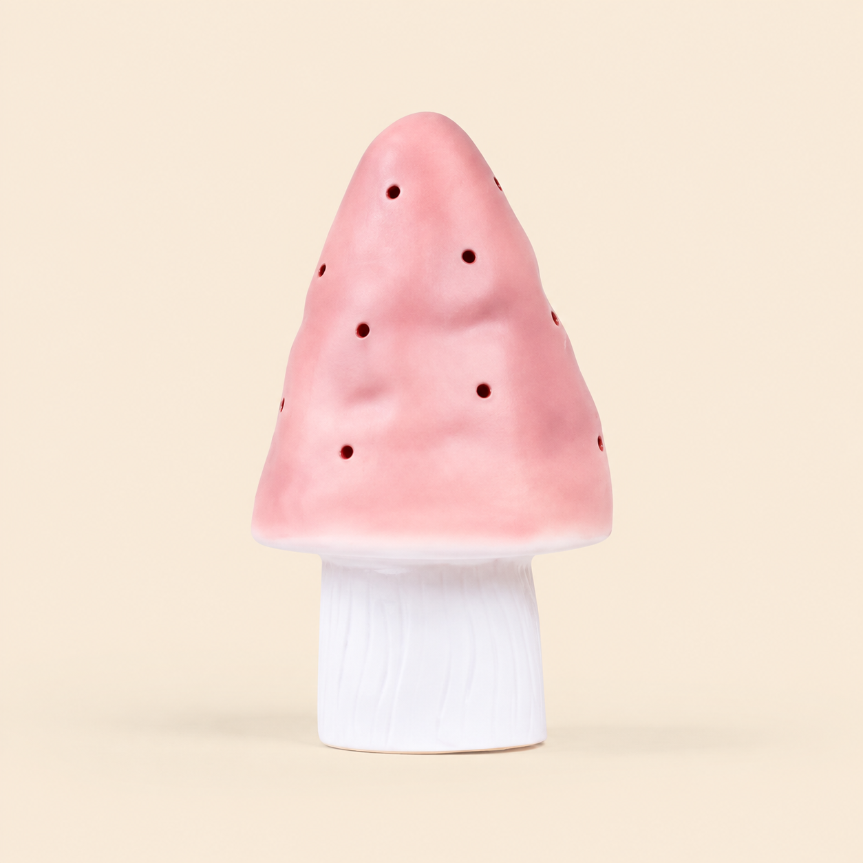 A mushroom-shaped night light with a pink perforated cap and a white cylindrical base, centered on a solid light beige background.