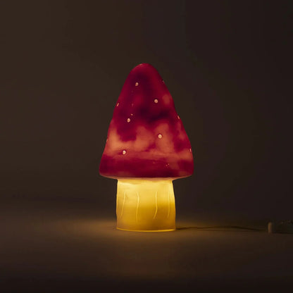 Mushroom-shaped lamp with pink cap and yellow base on a dark background