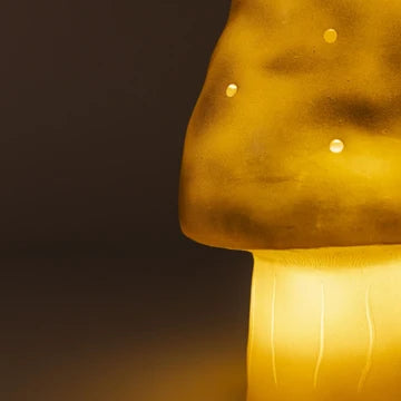 Mushroom-shaped lamp emitting a warm glow against a dark background