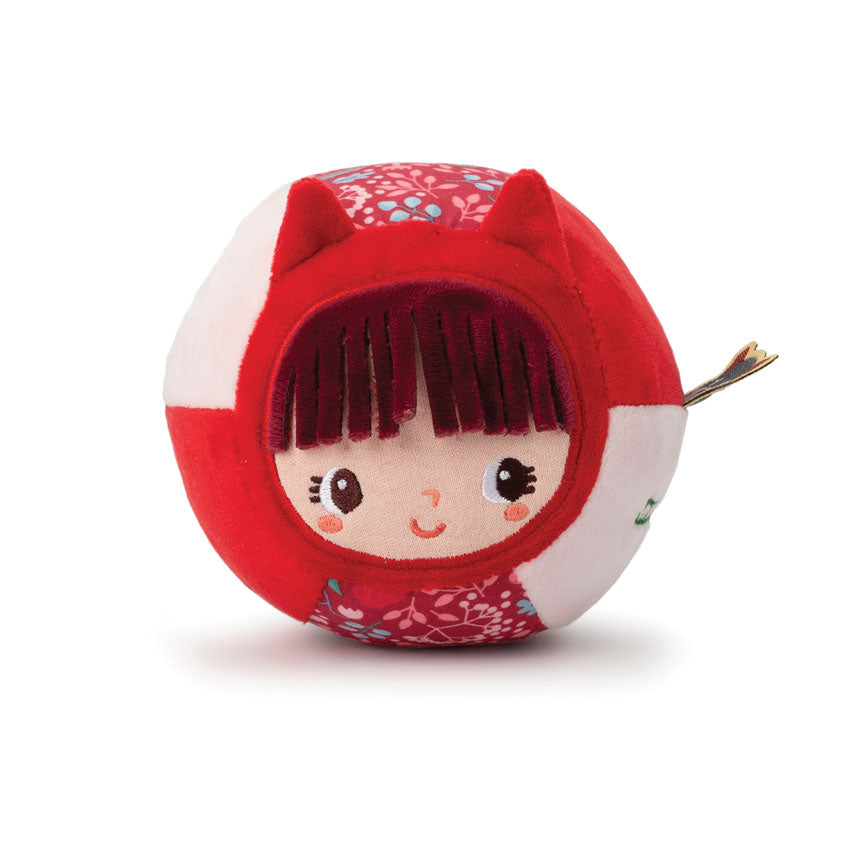 A plush toy resembling a red riding hood with a character's face inside, featuring various textures and a bell at the bottom.